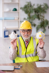 Old male architect holding respirator in the office