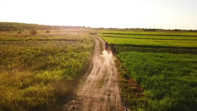 a motorcyclist in gear rides on a dirt road through a field