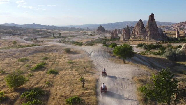 a company of young people extreme ride on quad bikes in the mountains of Cappadocia, shot from a drone
