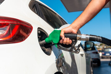 Hand of a man with the gun refueling gasoline or diesel fuel in a white car. Concept of...