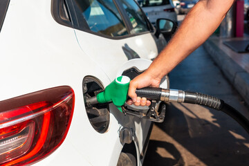 Close-up of a man's hand with the gun refueling gasoline or diesel fuel in a white car. Concept of transportation, energy crisis, oil crisis. Full tank in the midst of a price crisis at the gas pump