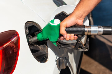 Close-up of a man's hand with the gun refueling gasoline or diesel fuel in a white car. Concept of transportation, energy crisis, oil crisis. Full tank in the midst of a price crisis at the gas pump