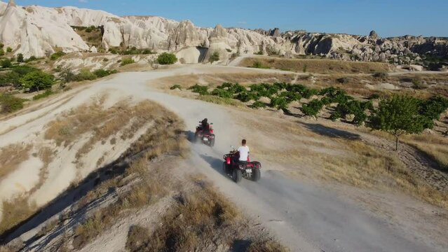 a company of young people extreme ride on quad bikes in the mountains of Cappadocia, shot from a drone