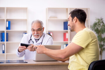 Obraz premium Young male patient visiting old male doctor