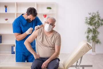 Old male patient visiting young male doctor in vaccination conce