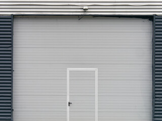Minimalistic photo of the metal garage door at the modern building with security camera placed above them	