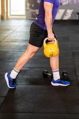 Side view of a young man in the gym with kettlebell