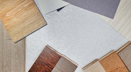 modern inspired interior finishing material samples for selection contains muti color wooden laminated flooring tiles, interior grey and beige wallpaper, vinyl flooring tile on stone background.