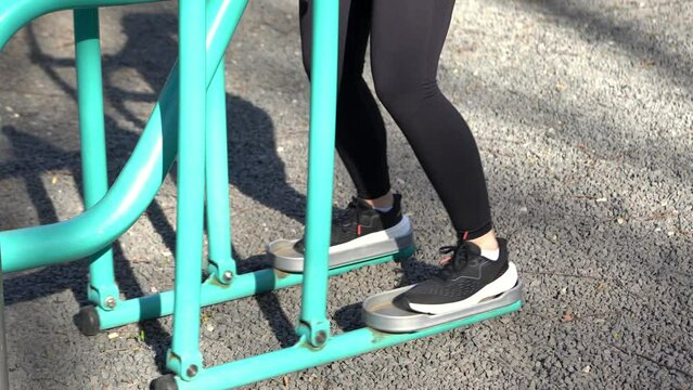 Sporty woman at fitness, training, sports and workout trains on a stepper or cross trainer outdoors in a park on a sunny day