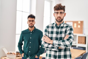 Young couple business workers standing with arms crossed gesture at office