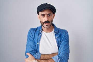 Hispanic man with beard standing over isolated background skeptic and nervous, disapproving expression on face with crossed arms. negative person.