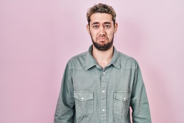 Fototapeta premium Hispanic man with beard standing over pink background depressed and worry for distress, crying angry and afraid. sad expression.