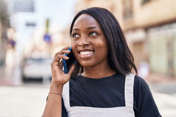 Young african american woman smiling confident talking on the smartphone at street