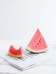 Vertical shot of slices of watermelon on a white wooden board on a white background