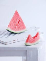 Vertical shot of slices of watermelon on a white wooden board on a white background