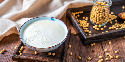 Many soybeans and a bowl of soy milk spilled on the table