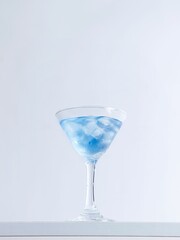 Vertical shot of a blue cocktail juice in a glass on a white surface on a white background