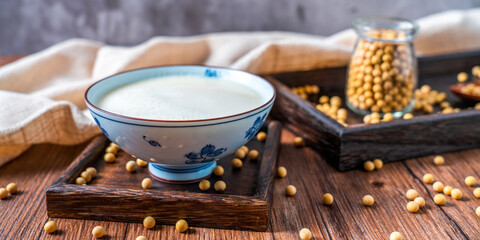 Many soybeans and a bowl of soy milk spilled on the table