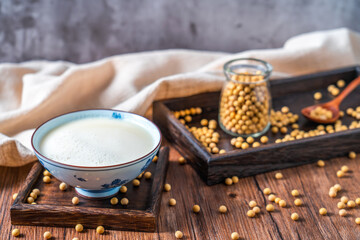 Many soybeans and a bowl of soy milk spilled on the table
