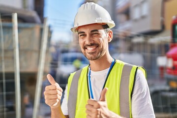 Young hispanic man architect smiling confident doing ok gesture with thumbs up at street