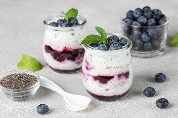 Chia pudding with blueberry and jam in two glass jars on gray background, Concept of healthy vegan breakfast