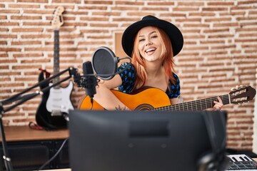 Young caucasian woman musician singing song playing classical guitar at music studio