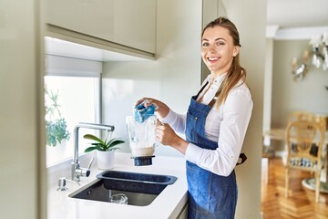 Young blonde woman smiling confident washing jar at kitchen