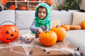 Adorable hispanic boy having halloween party holding sweets at home