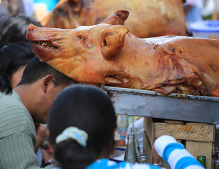 Roasted pork surrounded by costumers eating it in Otavalo market.