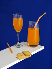 Keuken spatwand met foto Cups of Mimosa Cocktail drinks and Cracker Biscuit isolated on blue background © Jingluo/Wirestock Creators