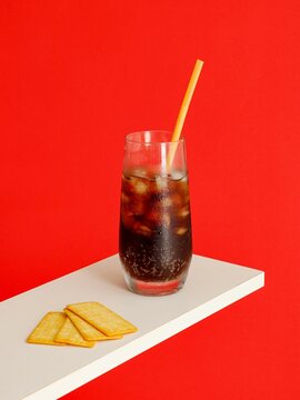 Naklejki Cold carbonated drink with ice cubes and Cracker Biscuit isolated on red background