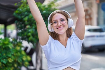 Young blonde woman smiling confident listening to music and dancing at street