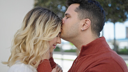 Obraz premium Man and woman couple smiling confident kissing on head at street