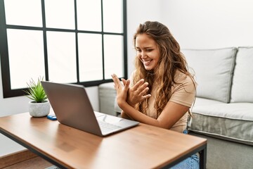 Young beautiful hispanic woman having video call communicate with sign deaf language at home