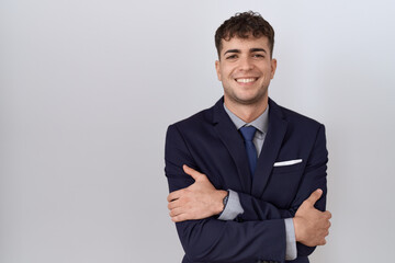 Young hispanic business man wearing suit and tie happy face smiling with crossed arms looking at the camera. positive person.