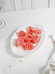 Vertical shot of a plate of red pomelo pieces on a white table