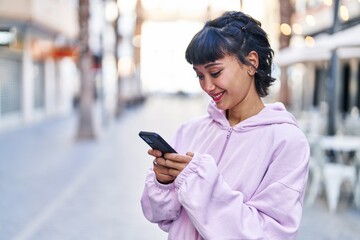 Young woman smiling confident using smartphone at street