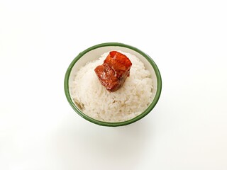 Close-up shot of steamed rice with pork belly in a bowl on white table