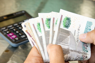 A man holding and counting Egyptian currency. The Egyptian economy, inflation, and currency exchange rate concept