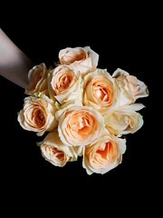 Vertical shot of a hand holding a bouquet of colorful roses in a studio in a dark background