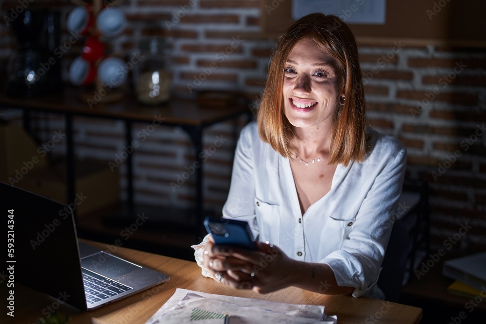 Canvas Prints Young redhead woman working at the office at night looking positive and happy standing and smiling with a confident smile showing teeth