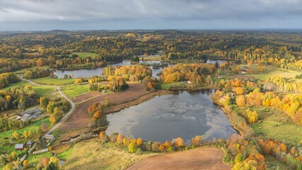 Fototapeta na wymiar Aerial of the beautiful lake surrounded by the colorful forest on a gloomy autumn day in Estonia