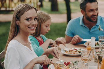 Happy family enjoying meal while having dinner outdoors together