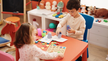 Adorable boy and girl playing with maths puzzle game and blocks toy at kindergarten