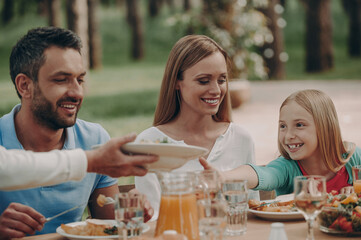 Beautiful family enjoying their meal and smiling while having dinner outdoors together