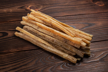 Close-up of dried salted tuna stripes on wooden background. Beer snacks, restaurant menu, salty seafood
