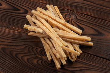 Close-up of dried salted tuna stripes on wooden background. Beer snacks, restaurant menu, salty seafood