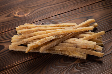 Close-up of dried salted tuna stripes on wooden background. Beer snacks, restaurant menu, salty seafood