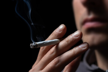 Smoking cigarette in the hand of young man close up