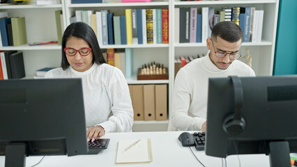 Man and woman students using computer studying at university classroom